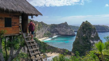 Rajalima 'daki Ağaç' ın merdivenlerinde duran bir turist. Rumah Pohon Hanesi, Atuh Sahili, Nusa Penida, Bali, Endonezya