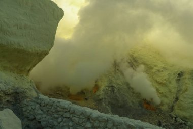 Kawah Ijen volkanik krater gölü ve zehirli sülfür dumanı işçiler bu dumanlı alandan sülfür çıkarıyorlar ve omuzlarında 3,5 km uzaklıktaki sepetleri boşaltıp bir sepet dolusu sülfür taşıyorlar.