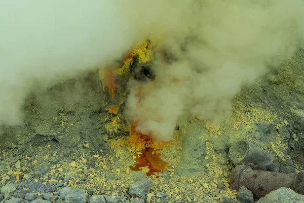 Kawah Ijen volcanic crater lake and toxic sulfur fume,workers extract sulfur from this smoky area and carry a-80-90 Kg.-basket full of sulfur on their shoulder and unload the baskets 3,5 Km away — стоковое фото