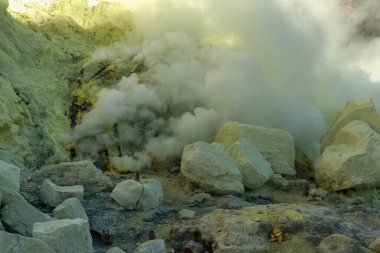 Kawah Ijen volkanik krater gölü ve zehirli sülfür dumanı işçiler bu dumanlı alandan sülfür çıkarıyorlar ve omuzlarında 3,5 km uzaklıktaki sepetleri boşaltıp bir sepet dolusu sülfür taşıyorlar.