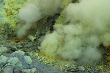 Kawah Ijen volkanik krater gölü ve zehirli sülfür dumanı işçiler bu dumanlı alandan sülfür çıkarıyorlar ve omuzlarında 3,5 km uzaklıktaki sepetleri boşaltıp bir sepet dolusu sülfür taşıyorlar.