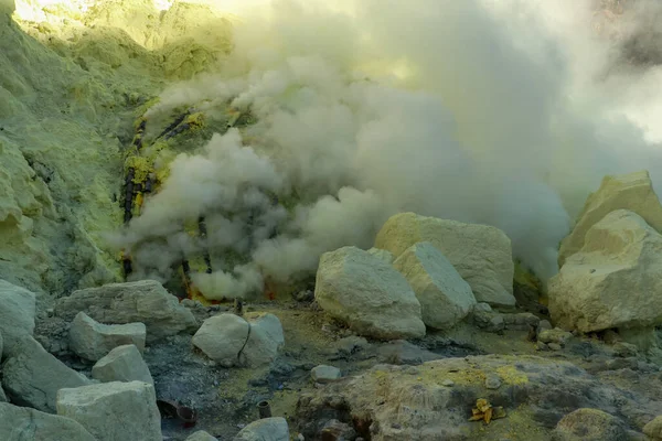 Kawah Ijen vulkanikus kráter tó és a mérgező kén füst, a munkások kivonják kén erről a füstös területen, és vigyenek egy-80-90 kg-os kosár tele kén a vállukon, és kirakodás a kosarak 3,5 km-re — Stock Fotó