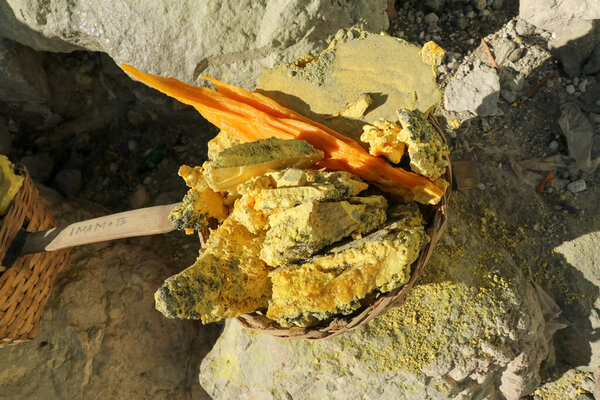 Heavy basket laden by pieces of natural sulfur to carry by miners from crater mine. Manual labour intensive sulphur mining operation in Kawah Ijen volcano. Popular travel destination, Java Indonesia