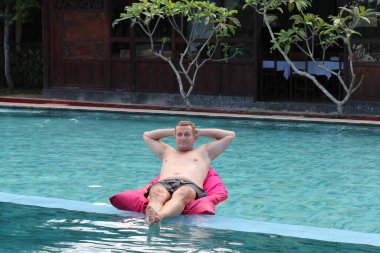 Havuzda şişme yatağı olan mutlu bir adam. Metin için boşluk