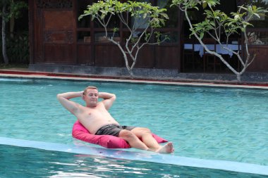 Havuzda şişme yatağı olan mutlu bir adam. Metin için boşluk