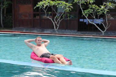 Zengin adam kendi yüzme havuzunda dinleniyor. Adam yüzme havuzunda hava yatağında dinleniyor. tatil ve boş zaman
