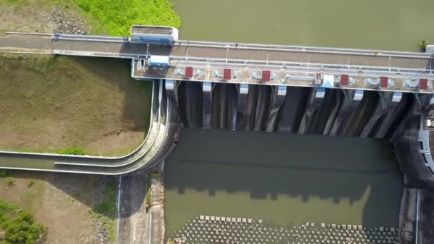 インドネシアのジャワ島のBendungan Sampean Baru上空の空中トップダウンドローン。コンクリート構造の水力発電生態再生可能エネルギーの上のアスファルト道路橋でダム貯水池の上に撮影 — ストック動画