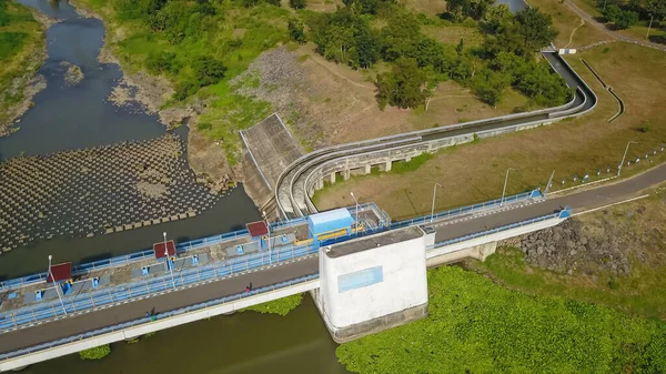 Aereo top down drone sopra Bendungan SamEuropean Baru a Java, Indonesia. Girato sopra un serbatoio della diga dell'acqua con il ponte stradale dell'asfalto sopra energia rinnovabile di ecologia idroelettrica con una struttura concreta — Foto Stock