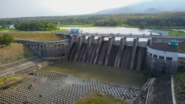 Hydroelectric dam with flowing water through gate, aerial view from drone. Bendungan Sampean Baru in Java, Indonesia — Stock Photo, Image