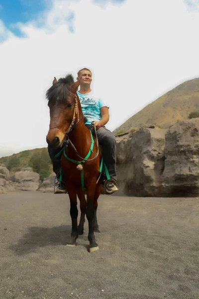 Mt.Bromo, Pasuruan, Java Oriental, Indonésia - 28 de maio de 2022. Homem a cavalo caminhando perto do templo hindu Pura Luhur Poten situado no sopé do vulcão Bromo, Bromo Tengger Semeru National Park — Fotografia de Stock