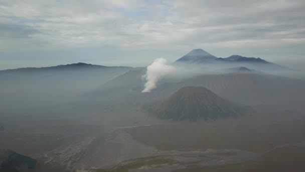 Vue d'en haut, vue aérienne imprenable sur le mont Batok et le mont Bromo éclairés par une journée ensoleillée. Le mont Bromo est un volcan actif dans l'est de Java, en Indonésie — Video
