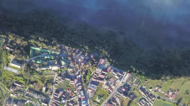 Luchtfoto vlucht over Cemoro Lawang, klein dorpje in de ochtendnevel. Waar gelegen aan de rand van massale Noord-Oosten van Mount Bromo, Oost-Java, Indonesië — Stockvideo