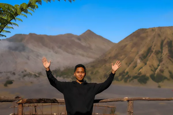 Szczęśliwy Azjata pozujący na Mount Bromo na tle jasnoniebieskiego nieba — Zdjęcie stockowe