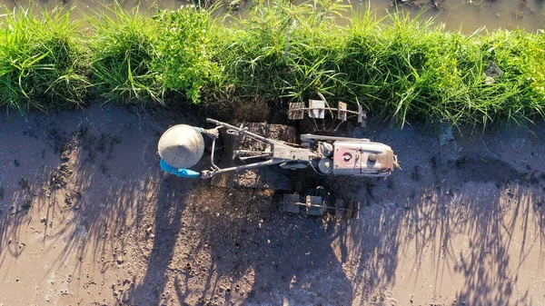 Tod down view to undefined Indonesian Farmer working with tractor on a ricefield. Drone aéreo disparado — Fotografia de Stock