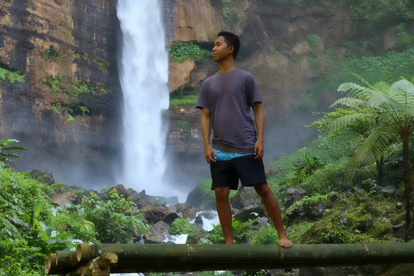 Wolny człowiek cieszący się pięknem natury. Mężczyzna relaks, stojąc w wodzie w pobliżu pięknego wodospadu na wakacjach letnich. Koncepcja wolności życia — Zdjęcie stockowe