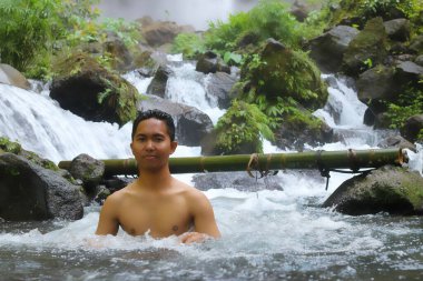 Mutlu Asyalı genç adam dere kanyon nehrinde dinleniyor. Orman, doğa manzarası. Soğuk su ve doğal spa prosedürü, vahşi yaşam ve yeşil turizm, aktif sağlıklı yaşam tarzı, yaz mevsimi