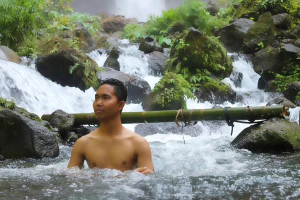 Szczęśliwy młody Azjata odpoczywający w strumieniu kanionu rzeki w tropikalnej dżungli, krajobraz natury. Zimna woda i naturalne zabiegi spa, dzika przyroda i zielona turystyka, aktywny zdrowy styl życia, lato — Zdjęcie stockowe