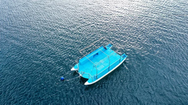 Drone aéreo de cima para baixo foto de catamarã pequeno ancorado no mar azul profundo. Um pequeno catamarã azul no mar aberto — Fotografia de Stock