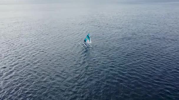 Vue aérienne arrière de la voile colorée de griffe de crabe sur le bateau en bois blanc Jukung près du rivage de Bali — Video