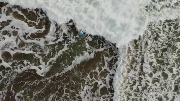 4k Top Down Aerial Shot of young boy with blue long shirt learning to surf in Canggu on Bali — Stock video