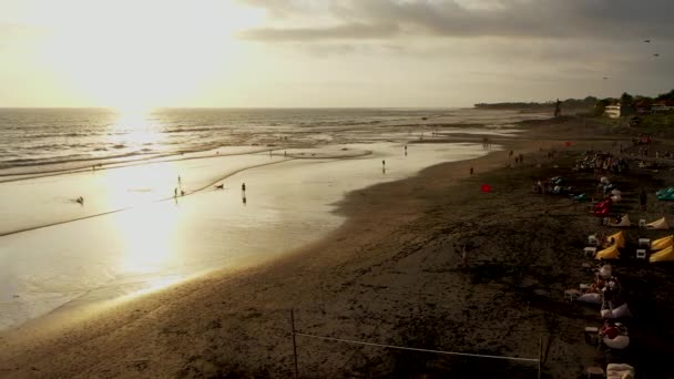 As pessoas apreciam o pôr-do-sol romântico na popular Echo Beach, em Canggu, na ilha tropical de Bali. Turista sentado e a pé na praia em Canggu, Bali, Indonésia — Vídeo de Stock