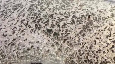 İHA görüntüsünün tepesinden küçük bir kız ve genç bir babanın sörf tahtasıyla oynamasına. Aile plajda SUP ile eğleniyor.
