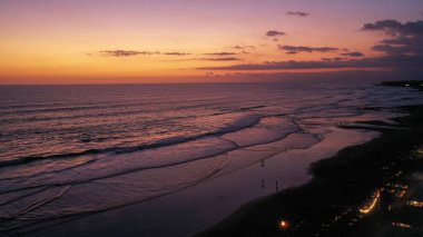 İnsanlar, Bali 'nin tropikal adasındaki Canggu' daki popüler Echo Beach 'te romantik günbatımının tadını çıkarıyorlar. Canggu, Bali, Endonezya sahillerinde oturan ve yürüyen bir turist