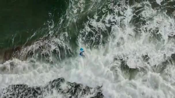 Młody surfer spaceruje po falach w płytkiej wodzie. Chłopak chodzi po oceanicznych falach. Nowoczesny aktywny styl życia. Obóz sportów wodnych. Ekstremalne wakacje. Nagranie z dronów lotniczych — Wideo stockowe