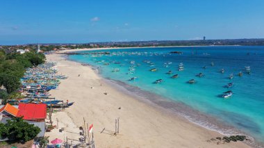 Arka planda geleneksel balıkçı teknesi olan tropikal kumsal deniz suyu ve güzel mavi gökyüzü.