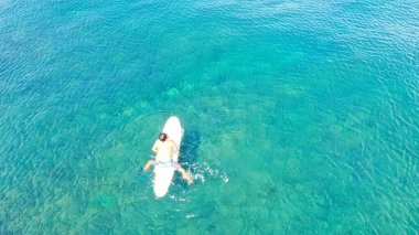 Turkuaz Suyu 'nda Sup Board' a binerken Sportif Genç Adam 'ın Havadan Görünümü. Şişirilebilir Sup tahtası ya da sörf tahtası, Su yüzeyinde sörf tahtası, İHA çekimi