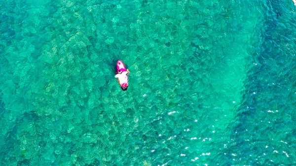Un surfeur solitaire est assis sur sa planche de surf en attendant une vague comme un spec dans la vaste surface de l'océan. Vue aérienne de l'homme assis sur le surf et naviguant dans la magnifique baie de la mer tropicale pendant les vacances d'été — Photo