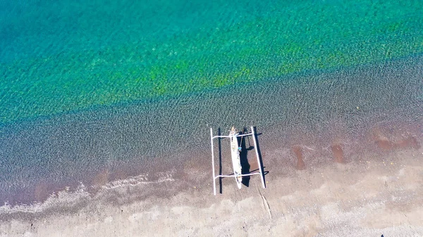 Veduta aerea dall'alto verso il basso della tradizionale barca in legno sulla spiaggia vulcanica di sabbia nera di Amed, Bali, Indonesia. Barche da pesca tradizionali chiamate jukung sulla spiaggia di sabbia nera — Foto Stock