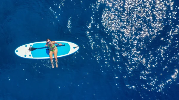 Jovem surfista sexy sentada em sua prancha de jantar olhando para o pôr do sol. Descanse no conceito de natureza. Tiro aéreo de cima para baixo — Fotografia de Stock