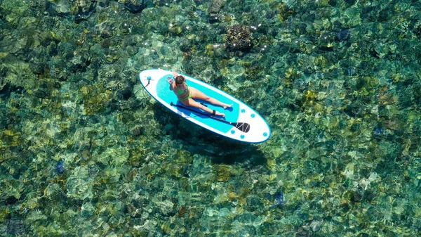 Tânăra femeie sexy surfer stând pe placa ei sup uitându-se la apus. Odihneşte-te la conceptul naturii. Aerian top jos împușcat — Fotografie, imagine de stoc