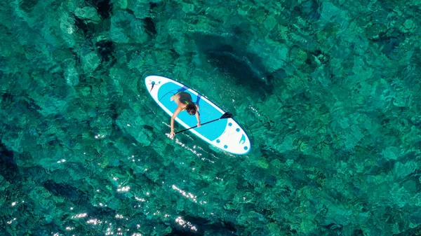 Vue aérienne d'oiseau de drone photo de jeune femme pratiquant la planche à pagaie ou le soup dans les eaux calmes cristallines tropicales des Caraïbes saphir — Photo