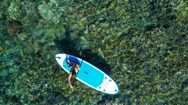 Vue du haut vers le bas image d'une femme pagayant sur ses genoux sur la planche à soup — Photo