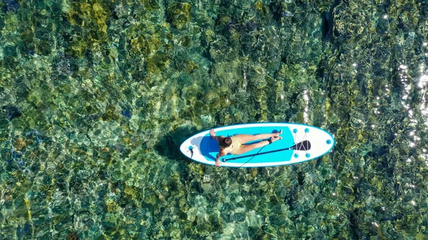 Приваблива жінка в бікіні купається на дошці для серфінгу, вид з повітря — стокове фото