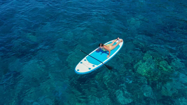 Belle femme en bikini bronzant sur une planche de surf, vue aérienne — Photo