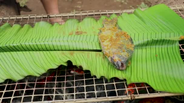 Peixes sendo grelhados em folha de banana na grelha de carvão. Peixe poleiro do Nilo fresco do mar. Frutos do mar — Vídeo de Stock