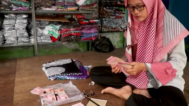 A hidzsábba öltözött muszlim nő megszámolja a rúpia bankjegyeket. Indonéz rúpia pénz koncepció — Stock videók