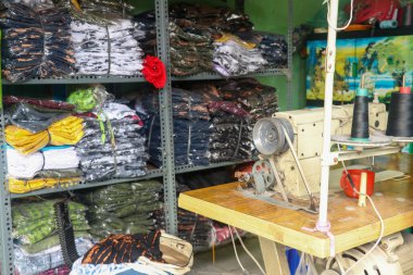 Arka planda kumaş yığınları olan terzi atölyesinde dikiş makinesi..