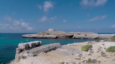 Eski İngiliz dönemi Torre des Castellar körfezin kıyısında, Cuitadella yakınlarında, parlak mavi deniz ve yaz bulutlarıyla. Torre des Castellar Torre Santandria