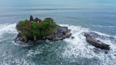 Güçlü okyanus dalgaları Endonezya, Bali 'deki Tanah Lot tapınağıyla kayalık kayalıklara çarpıyor. Denizdeki ünlü turizm merkezini çevreleyen hava görüntüleri.