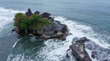 Güçlü okyanus dalgaları Endonezya, Bali 'deki Tanah Lot tapınağıyla kayalık kayalıklara çarpıyor. Denizdeki ünlü turizm merkezini çevreleyen hava görüntüleri.