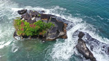 Güçlü okyanus dalgaları Endonezya, Bali 'deki Tanah Lot tapınağıyla kayalık kayalıklara çarpıyor. Denizdeki ünlü turizm merkezini çevreleyen hava görüntüleri.