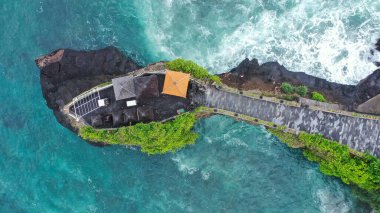 Tanah Lot adlı ünlü balerin tapınağının tepeden aşağı manzaralı fırtınalı bir havada büyük dalgalarla. Endonezya 'nın en üst simgesi.