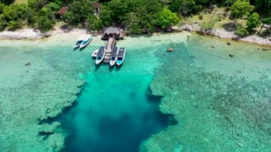 Menjangan adasında mavi denizde iskelede turistik tekneler. Havadan görünüm