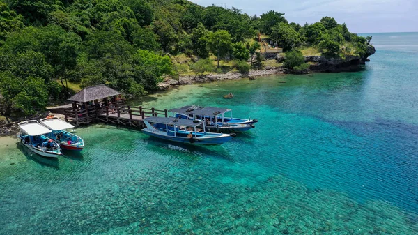 Endonezya, Bali 'deki Menjangan Adası' nın kıyısına park etmiş bir tekne. Denizdeki mercan kayalıklarına parkedilmiş tekneler. Güzel ve temiz su. Sahilde ağaçlar var. Tatil cenneti
