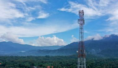 Altın saat boyunca yeşil ormanlarla kaplı tepenin tepesindeki 4G ve 5G Telekom Kulesi 'nin hava görüntüsü.