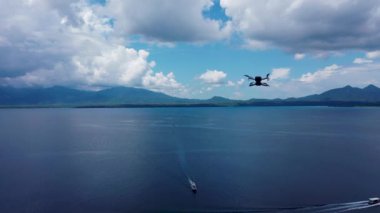 Beyaz İHA Doğada Uçuyor. Uçan Helikopterde İHA asılı. Dron Uzaktan Kumandalı Hava Dronu.